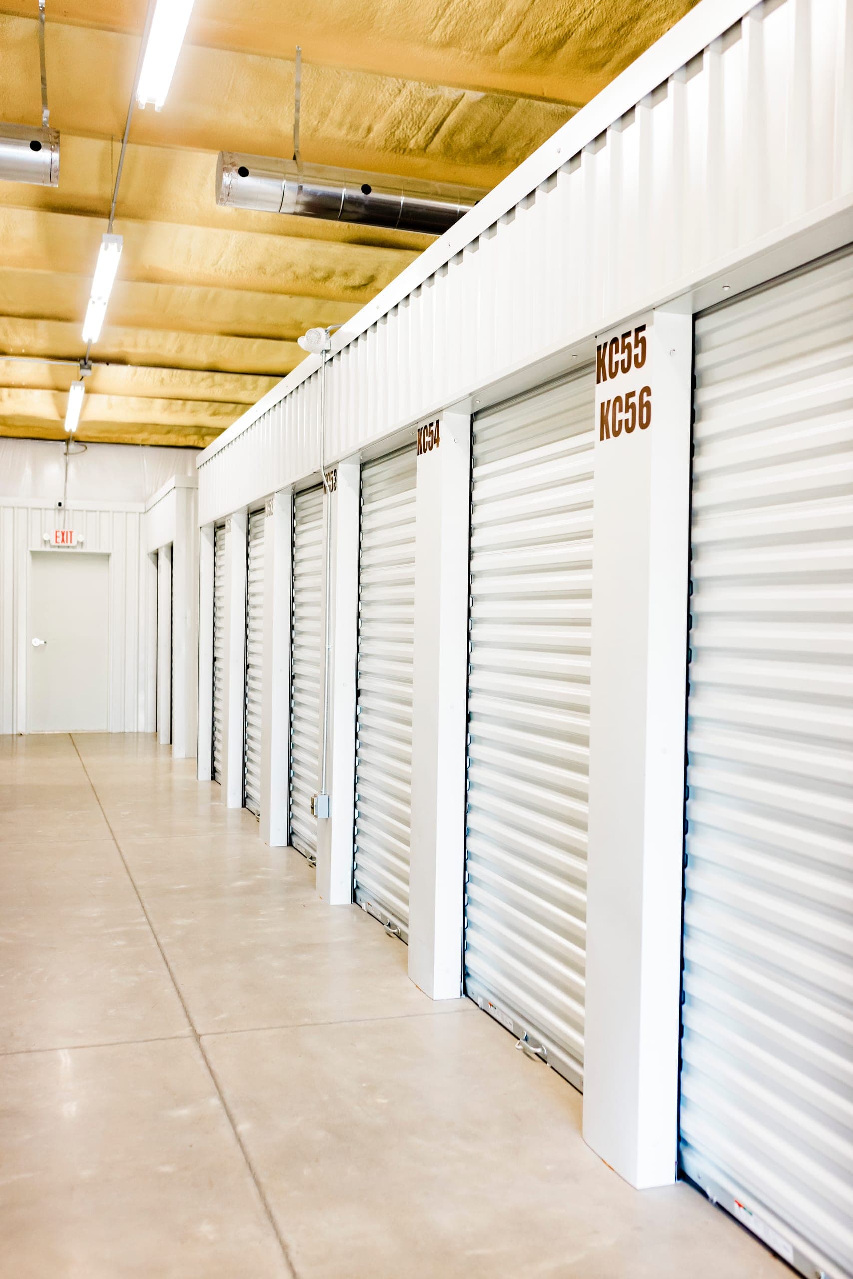 Indoor climate-controlled hallway lined with white roll-up storage unit doors